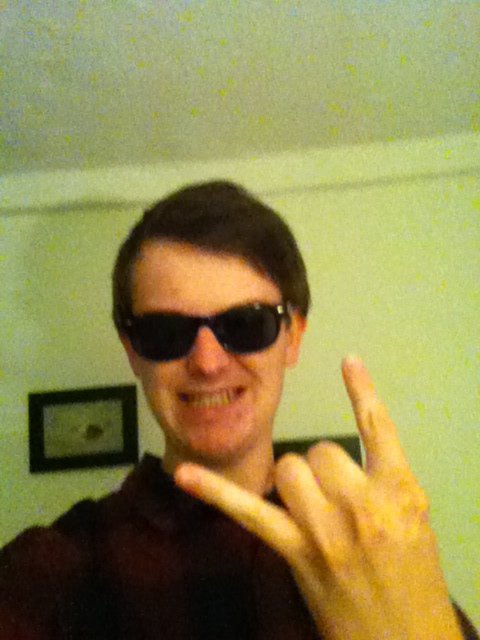 Noisy selfie of a teenager wearing sunglasses indoors